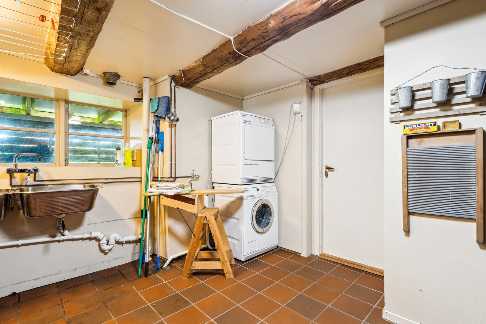 I hovedhusets kjeller er det vaskerom med flislagt gulv, malte plater på vegger og plater/bjelker i innvendige tak. Rommet har 2 skyllekar og opplegg for vaskemaskin. Galleribilde