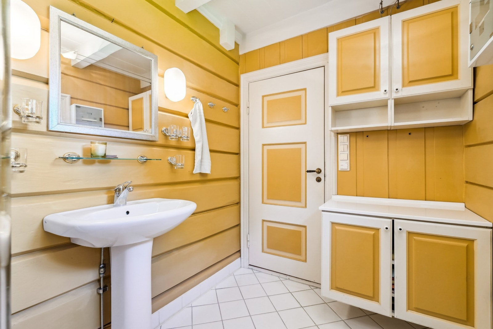 Badet i 1. etasjen har flislagt gulv med gulvvarme og malte tømmervegger. Panelt himling. Galleribilde