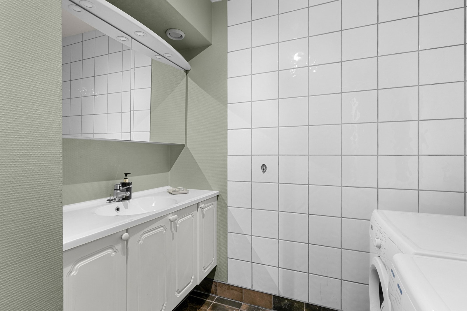 Badet er utstyrt med duskabinett, veggmontert servantinnredning og opplegg for vaskemaskin Galleribilde