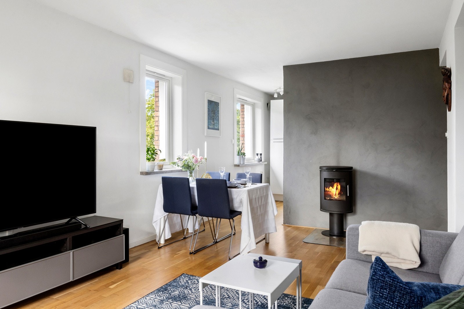 Åpen løsning mot kjøkkenet der en praktisk halvvegg skjermer arbeidsområdet, gir rommet både lys og luft, og legger til rette for sosial matlaging - uten at oppvasken stjeler oppmerksomheten. Galleribilde