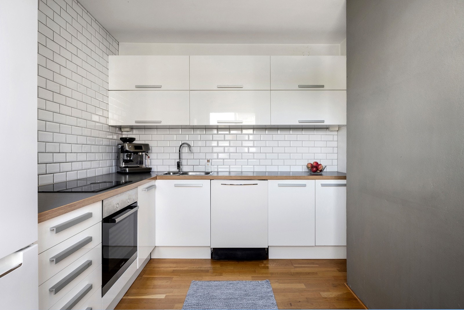 Lyst kjøkken med god skap- og benkeplass. Det er fliser mellom kjøkkenbenk og overskap. Galleribilde