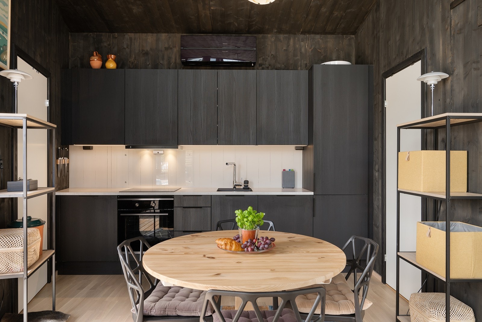 Innredningen har et lekkert, moderne design med sorte, glatte fronter og lys laminatbenkeplate med mørk oppvaskkum. Galleribilde