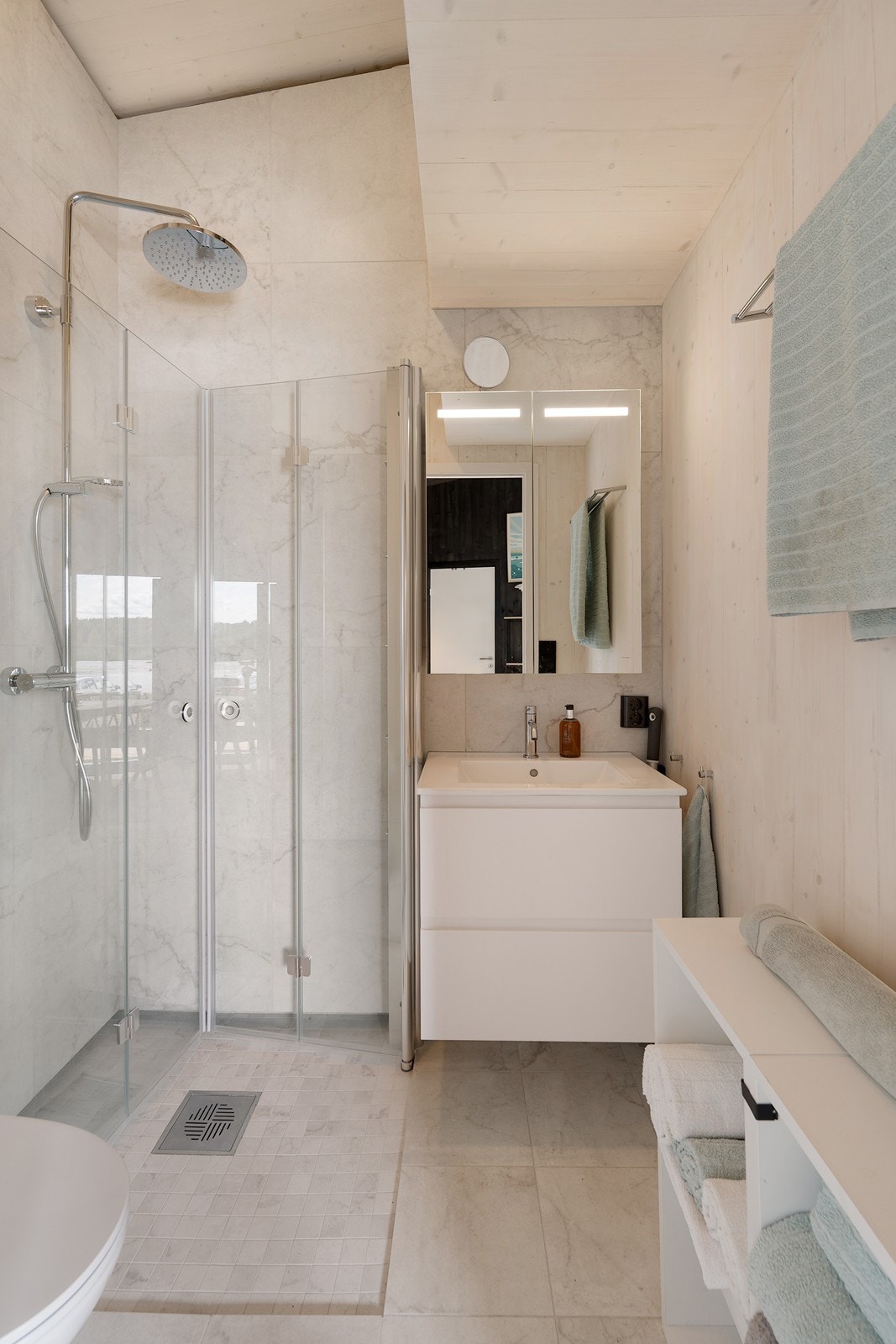 Toalettet er vegghengt, dusjhjørnet har regnfallsdusj og innfelbare glassdører.
Innredningen har hvite, glatte skuffefronter, heldekkende servant og speilskap med integrert belysning. Galleribilde