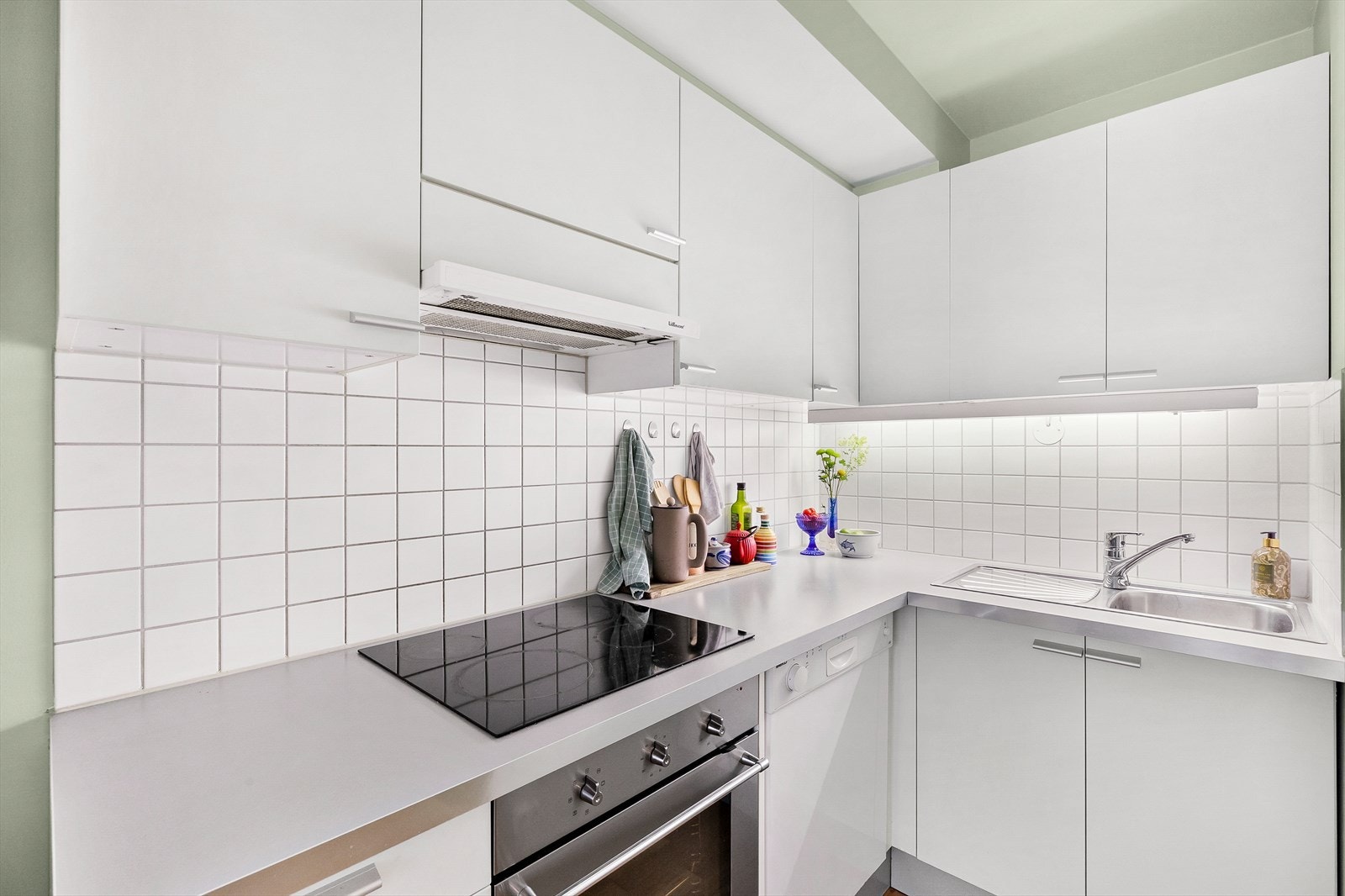 Lys kjøkkeninnredning med hvite, slette fronter og medfølgende hvitevarer Galleribilde