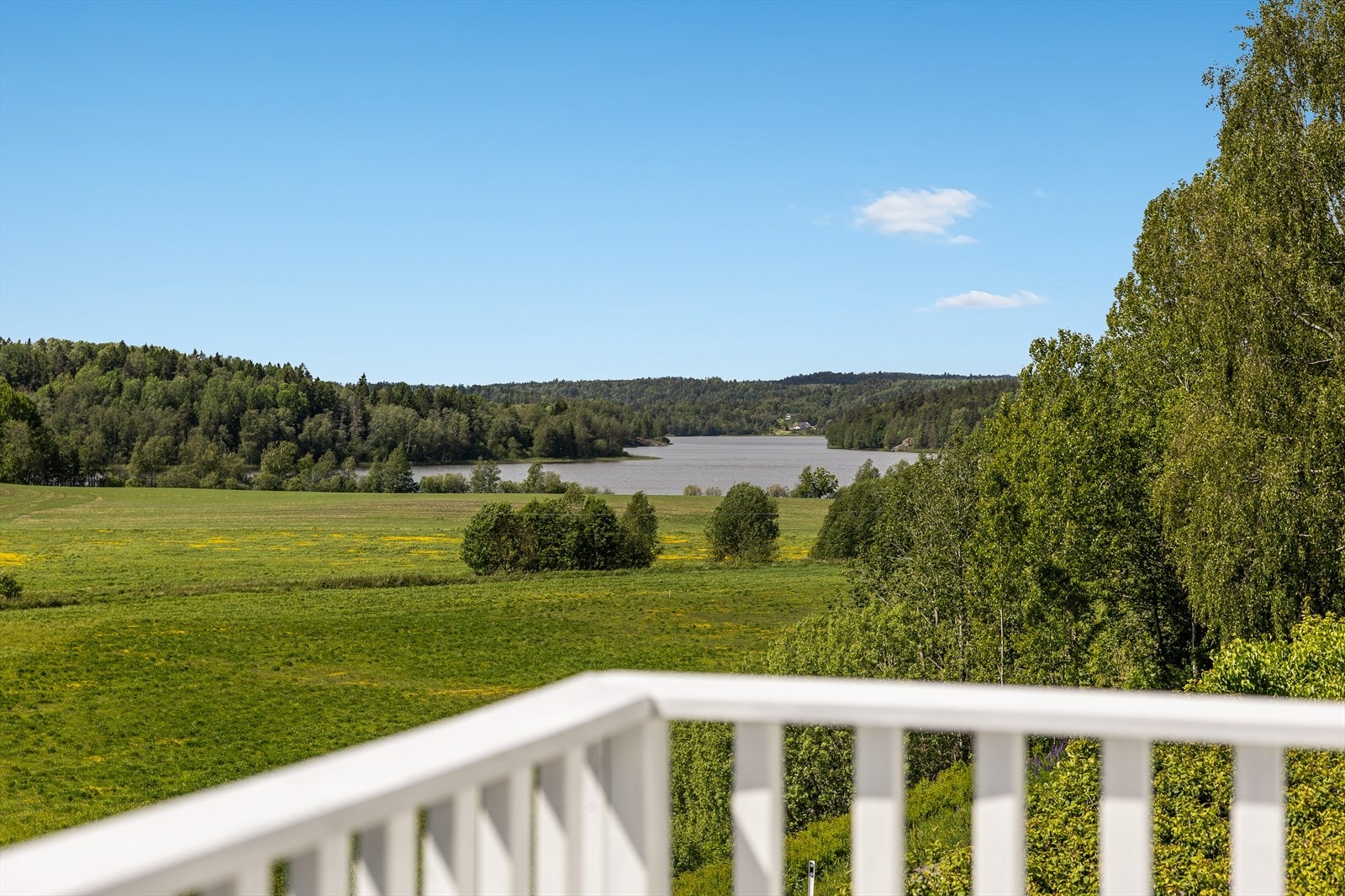 Åpent kulturlandskap og utsyn mot nærliggende vann og åser Galleribilde