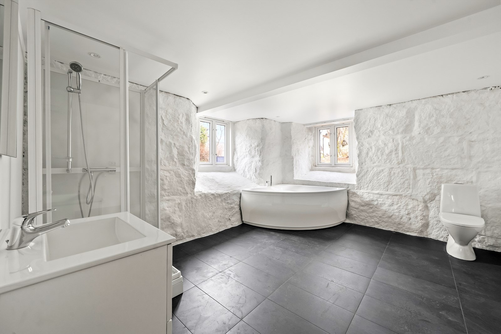 Oppgradert bad med fliser på gulv med varmekabler og originale murer som er behandlet. Rommet er innredet med baderomsinnredning, toalett, dusjkabinett og badekar. Galleribilde