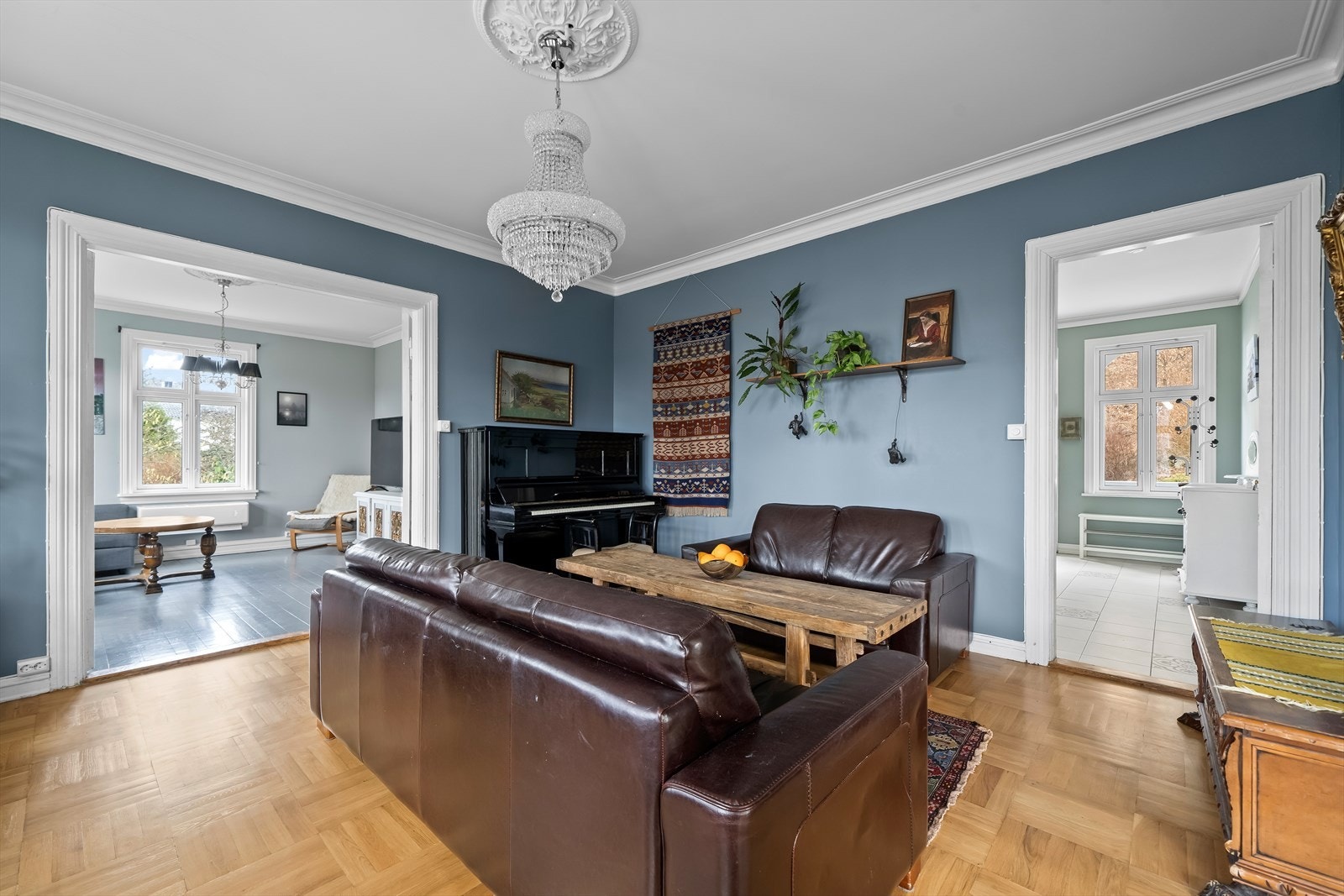 Romslig stue med harmoniske farger, store vinduer og takdekor. Galleribilde