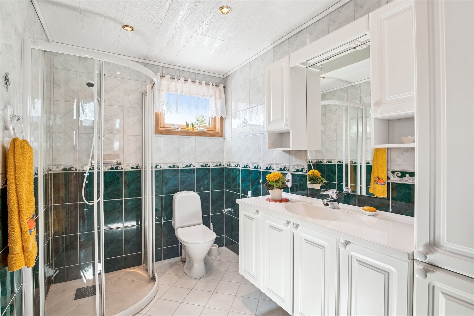 Badet i hytta er romslig og har flislagte gulv- og vegger, dusjnisje, toalett og en baderomsinnredning som gir god plass til oppbevaring av håndklær og hygieneartikler. Galleribilde