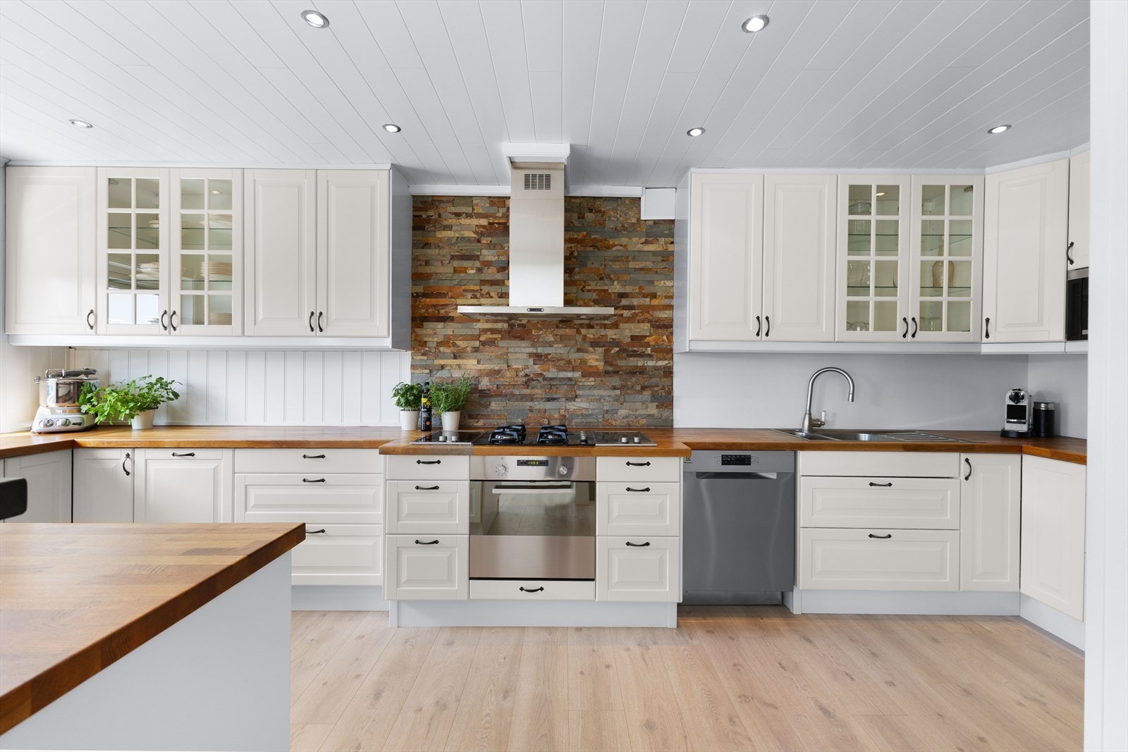 Kjøkkenet har lyse profilerte fronter, heltre benkeplate og oppvaskkum. Det er skiferfliser på vegg bak platetopp og malte våtromsplater bak oppvaskkum. Galleribilde