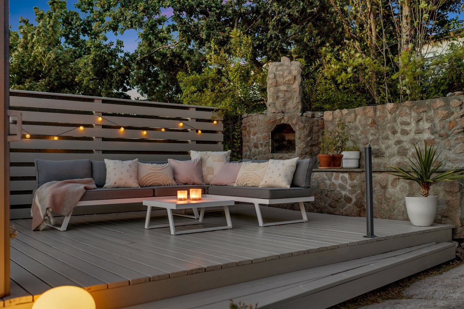 Herlig utesone med treplatting og plassmurt ildsted. Galleribilde