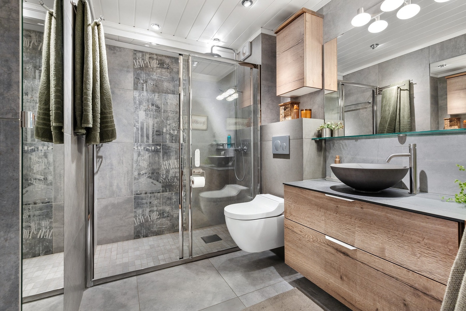 Rommet er innredet med dusjnisje og skyvedører i glass, vegghengt toalett med innebygd spyling fra 2024 og innredning med bollevask fra 2023, komplett med speil Galleribilde