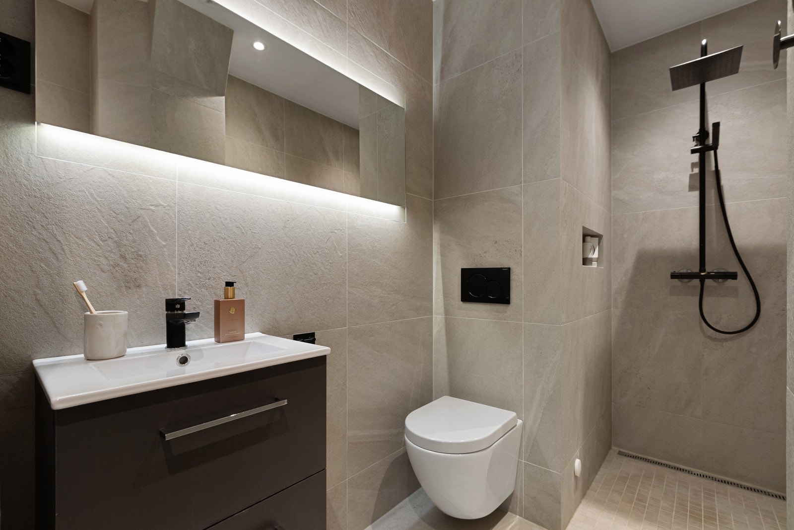 Flislagte overflater og elektriske varmekabler gir både et pent uttrykk og god komfort. Innredningen består av nedfelt servant, veggmontert toalett Galleribilde