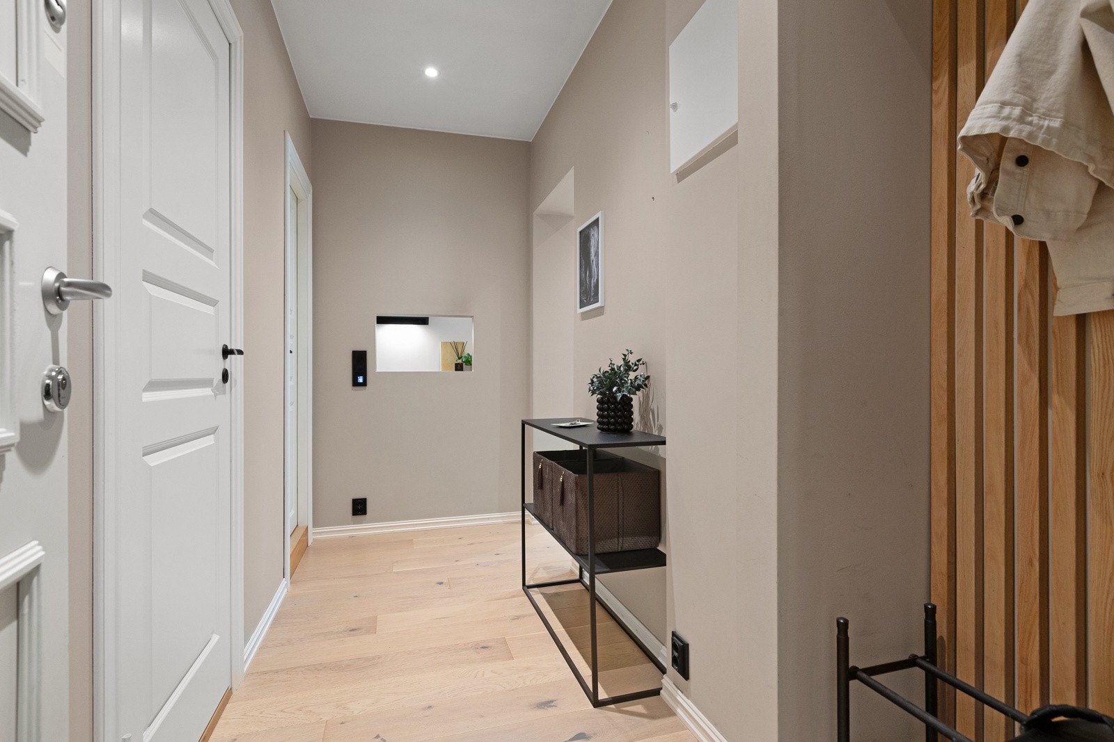 Flott entré med lyse vegger og parkettgulv, speil, veggpanel og belysning. Galleribilde