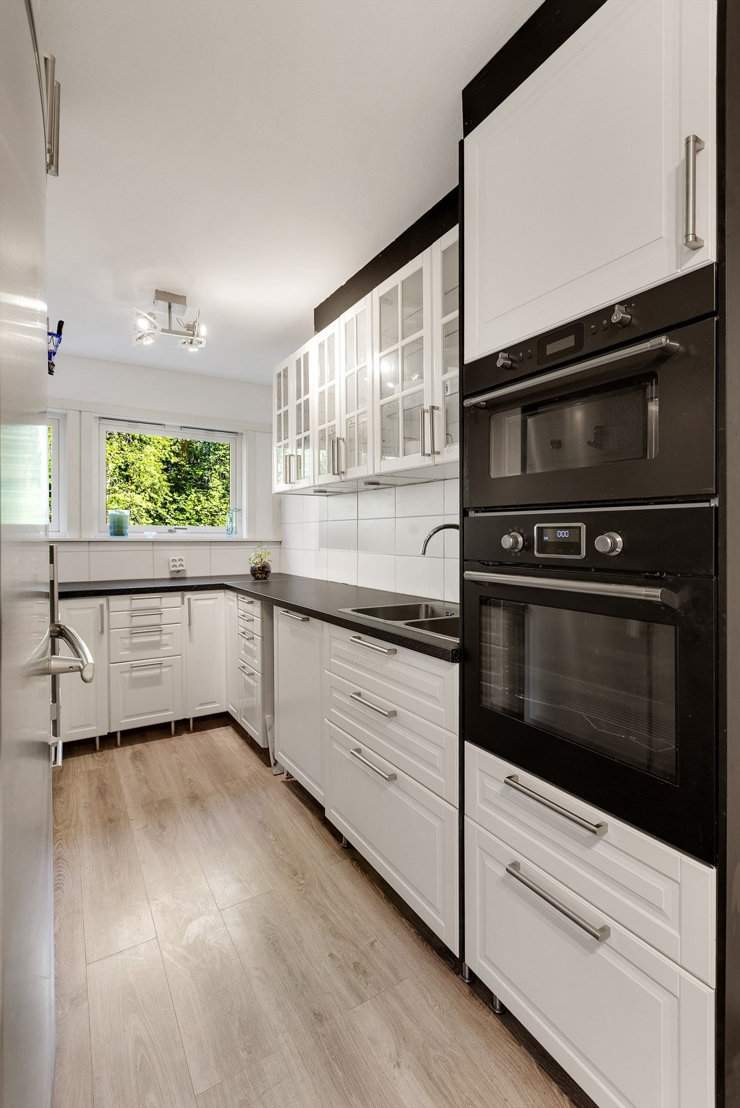 Kjøkkenet har stilren innredning fra IKEA med lyse, profilerte fronter og laminert benkeplate. Løsningen er både praktisk og innbydende, med godt med skap- og benkeplass, belysning under overskap og ventilator med kullfilter. Galleribilde