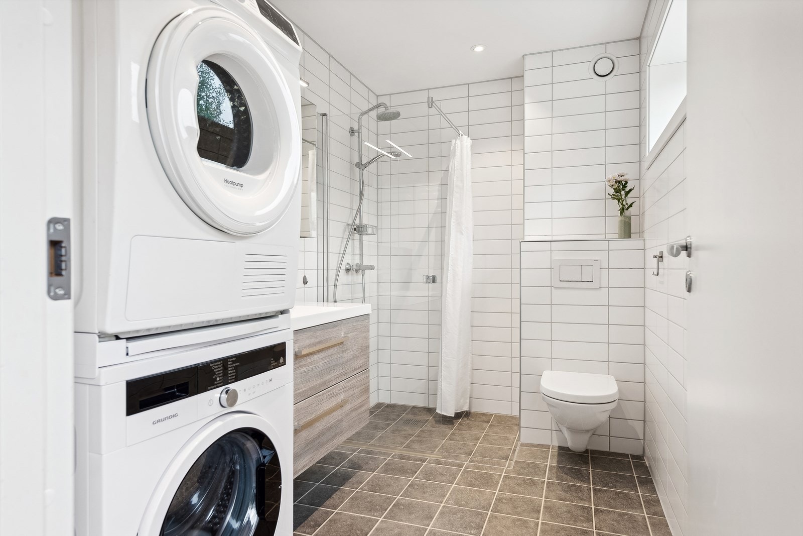 Innredningen består av speil, servant med skuffeseksjon, veggmontert toalett, dusjhjørne og opplegg for vaskemaskin. Galleribilde