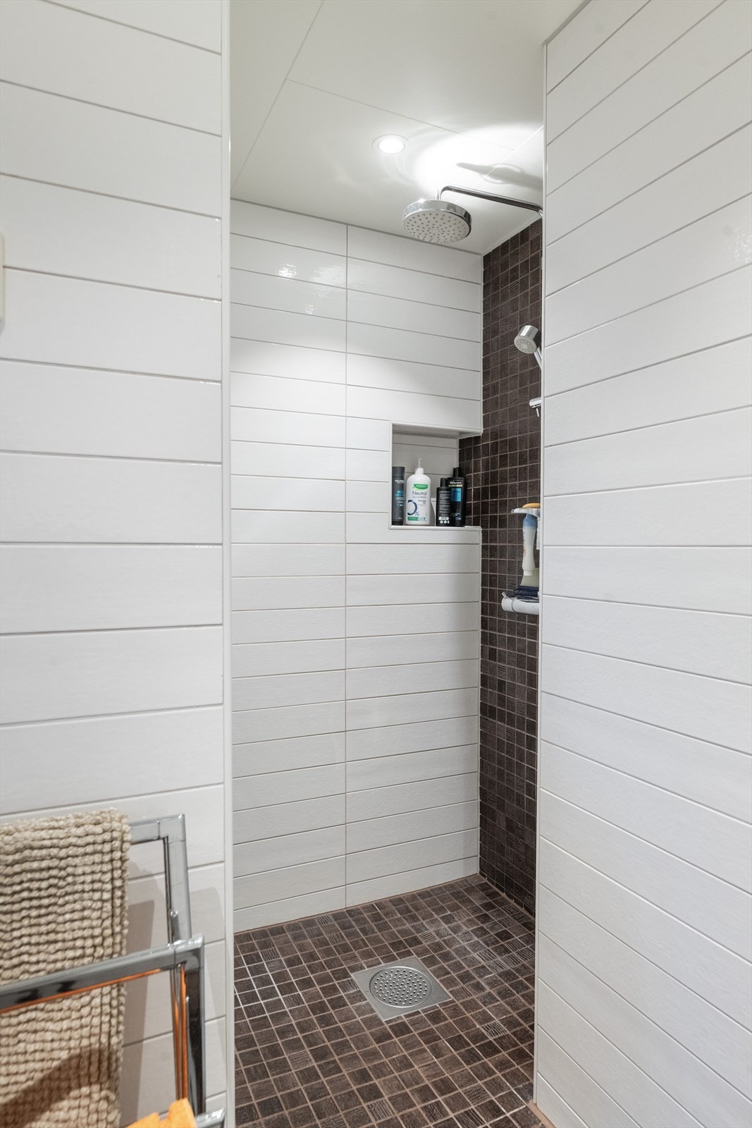 Integrert belysning i himling. Fin dusjnisje innerst i rommet med armatur på vegg. Galleribilde