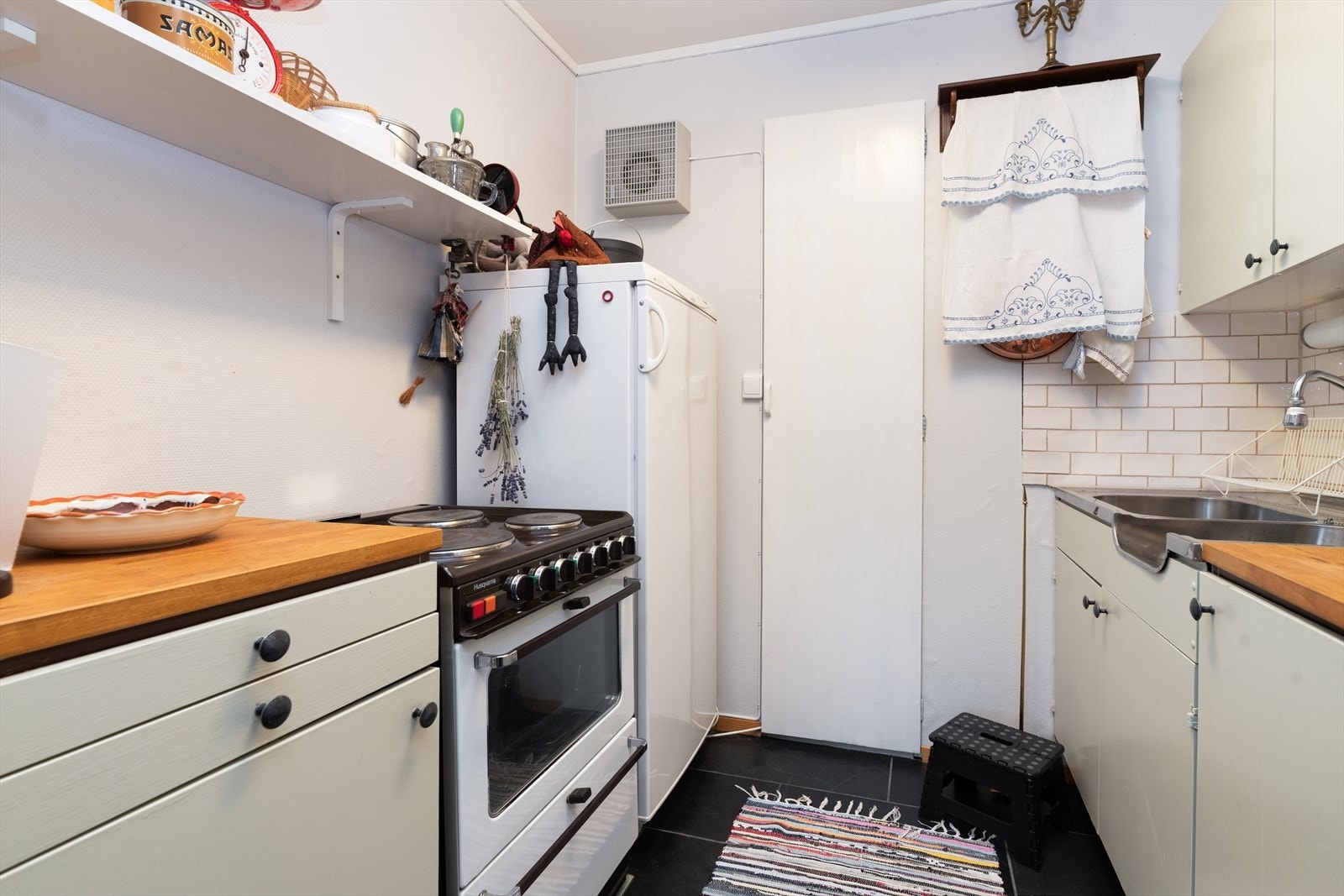 Tilliggende stuen er det åpent mot et lite kjøkken, da deler av kjelleren tidligere har vært adskilt som egen hybel. Skapdør med tilkomst inn til en liten bod på innsiden. Galleribilde