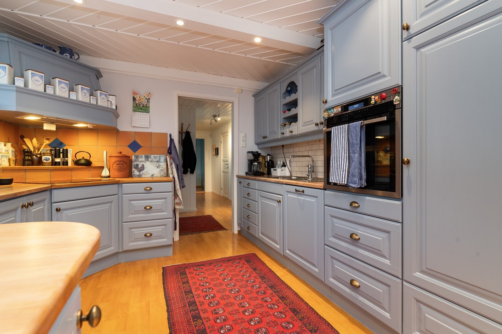 Ved kokesone og oppvaskbenk er det flis på veggflatene over. Det er nedfelt oppvaskkum med to kummer og avrenningsflate, nedfelt induksjonstopp fra 2018, integrert stekeovn i praktisk ståhøyde, integrert oppvaskmaskin og kjøleskap. Galleribilde