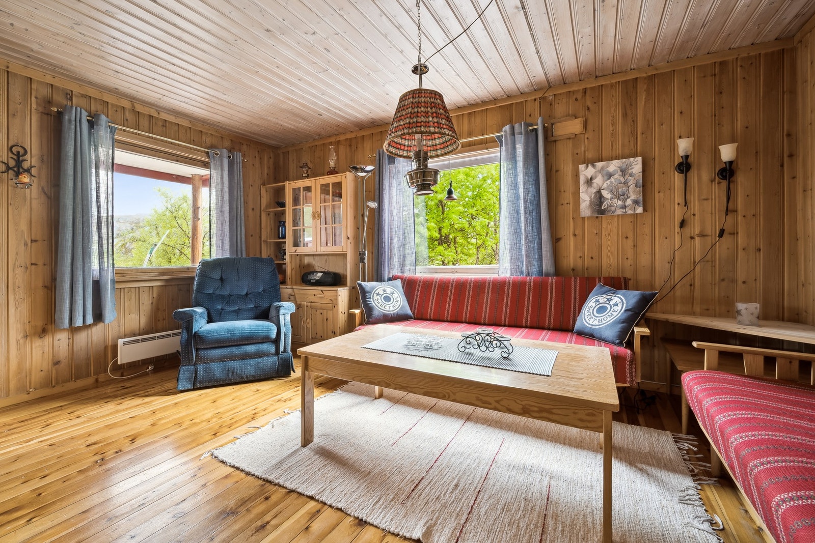 Koselig stue i tradisjonell hyttestil - med gjennomgående bruk av tre i både himling, vegger og gulv som skaper en lun og innbydende atmosfære. Galleribilde