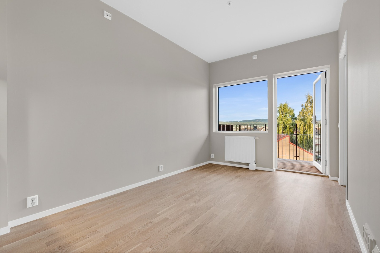 Lys og trivelig stue med god plass til sofagruppe - store vindusflater og åpen planløsning gir en luftig atmosfære, mens utgangen til østvendt balkong inviterer dagslyset inn og skaper en naturlig forlengelse av oppholdsrommet. Galleribilde