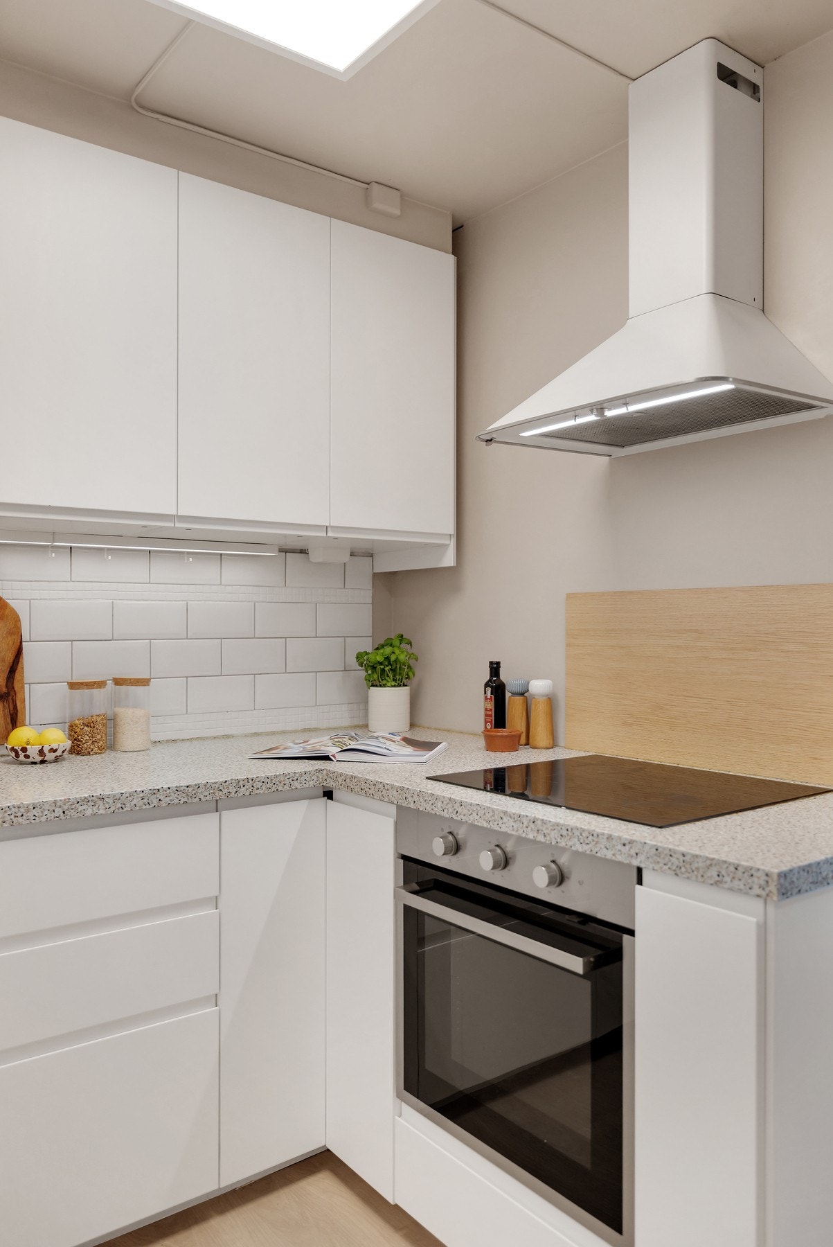 Integrerte hvitevarer med innfelt platetopp i benkeplate, komfyr og kjøl/frys. Det er installert en mini oppvaskmaskin på kjøkkenbenken. Galleribilde