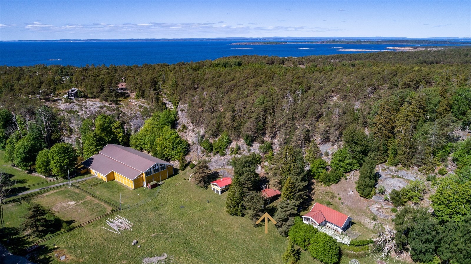 En slette strekker seg mellom Fjordhotellet og Varmbadbukta. Her, med ryggen til Bloksberg, ligger hytta fra 1964, godt skjermet for innsyn fra bak furutrær og bjørk. Galleribilde