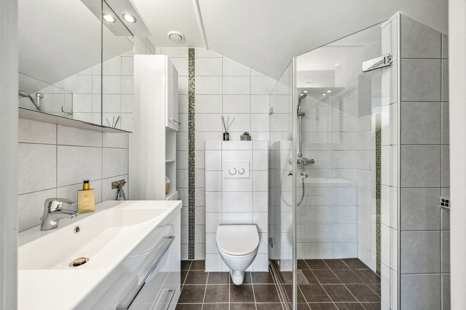 Flislagt bad med dusjhjørne, servant med innredning, speil og mekanisk avtrekk. Galleribilde