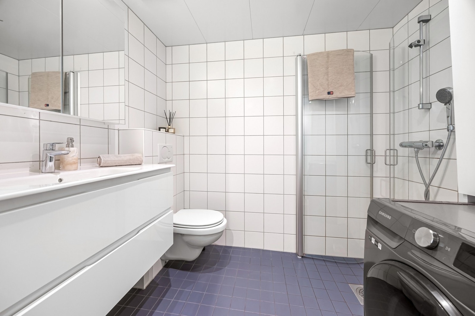 Flislagt bad med varmekabler i gulv og opplegg for vaskemaskin. Galleribilde