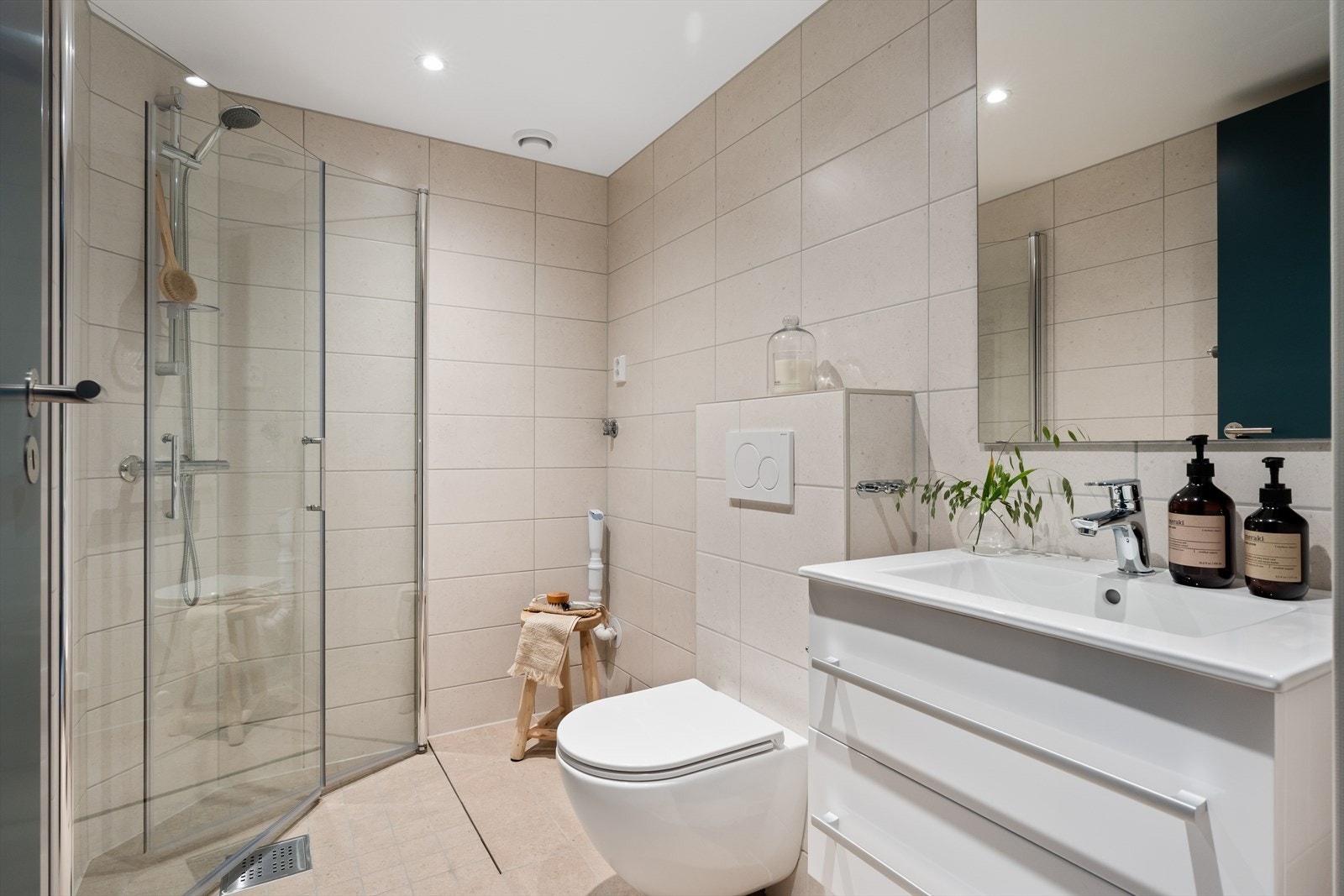 Badet er lekkert og tidløst med helflisede overflater, behagelig gulvvarme og innfelte downlights i taket. Galleribilde