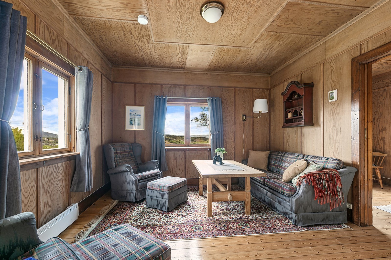 Koselig stue i tilknytning til kjøkkenet, med tregulv, vedovn og panelvegger. Galleribilde