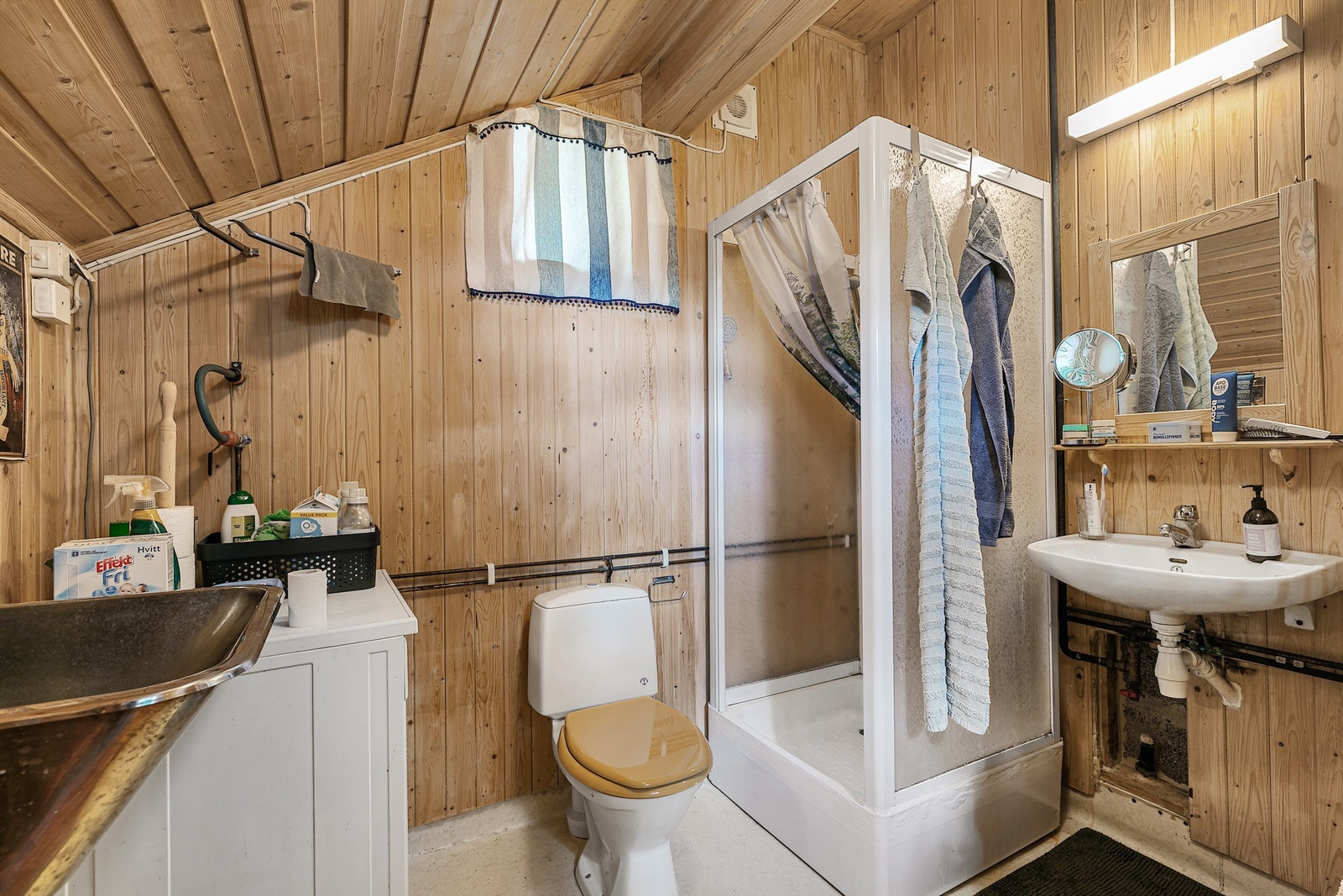 Badet har gulvbelegg, panelvegger og varmekabler. Innredet med dusjkabinett, toalett og enkel servant med speil og belysning. Opplegg for vaskemaskin er etablert. Galleribilde