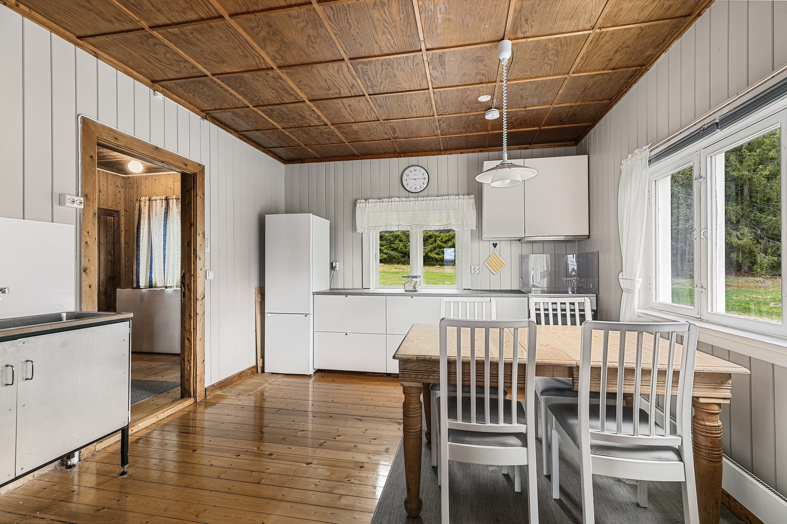 Innredet med dobbel oppvaskkum, laminert benkeplate, og plass til komfyr og kjøleskap. Enkel avtrekksvifte montert over kokesonen. Galleribilde