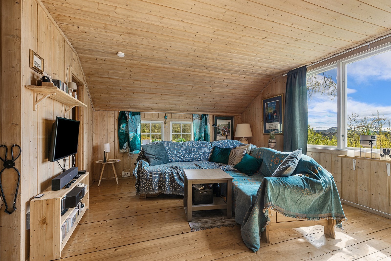 Stuen har en åpen løsning med naturlig materialbruk og gode lysforhold. Vedovnen tilfører både varme og sjarm. Galleribilde