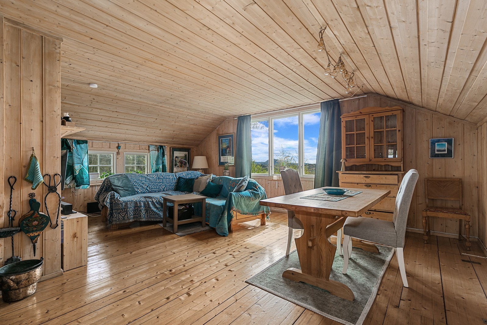 Lys og koselig stue med tregulv og panelvegger i naturlig tre. Store vindusflater gir godt med dagslys og utsyn til uteområdet. Galleribilde