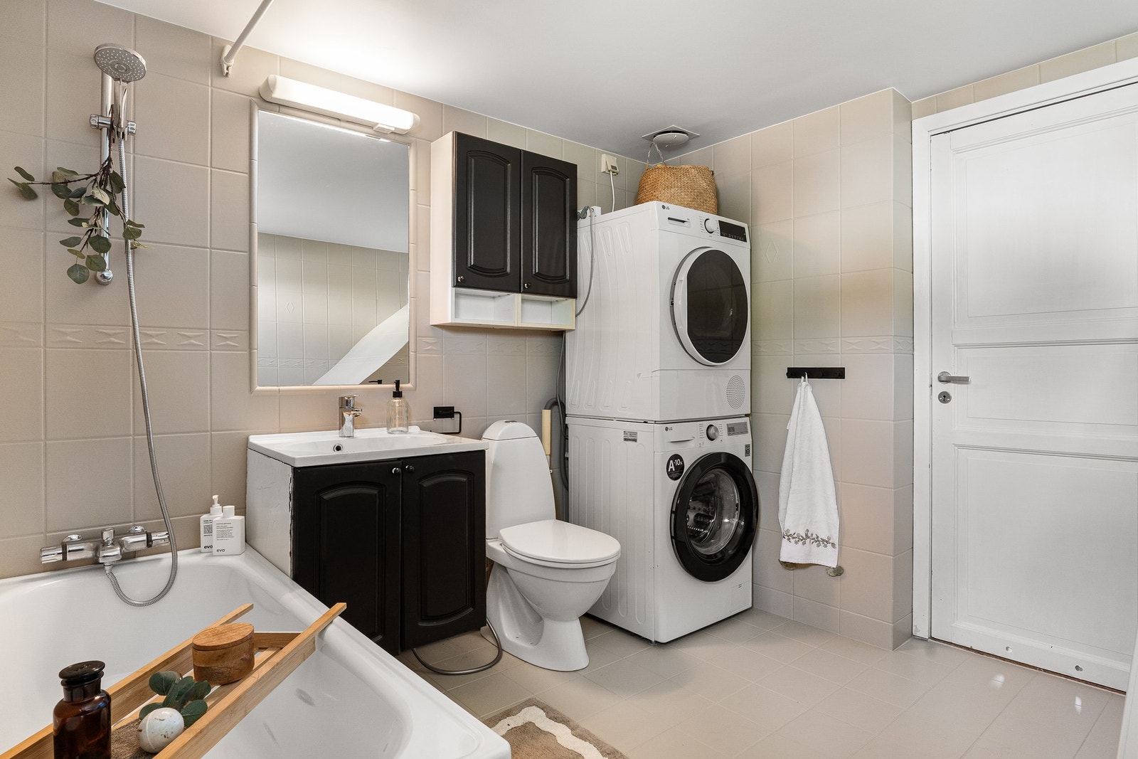 Eldre, men funksjonelt baderom utstyrt med badekar med dusj, servant med underskap og speil og toalett Galleribilde