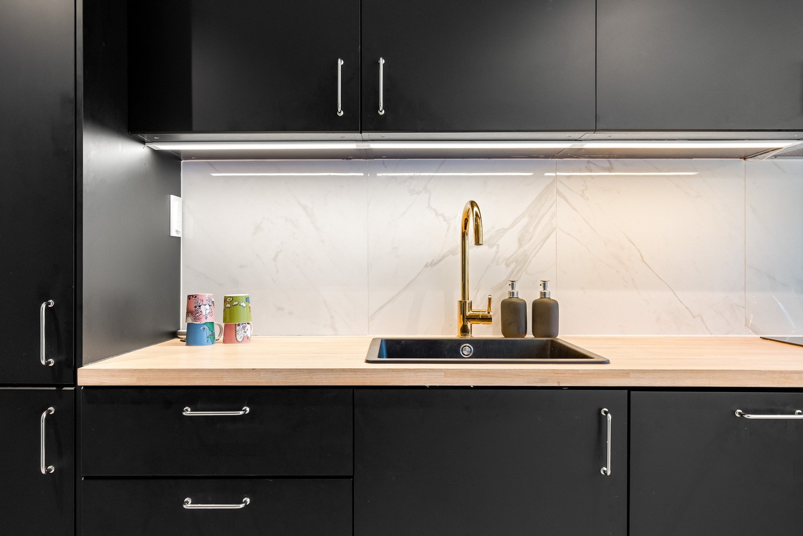 Kjøkkeninnredningen har sorte, slette fronter og heltre benkeplater med nedfelt oppvaskkum i kompositt. Galleribilde