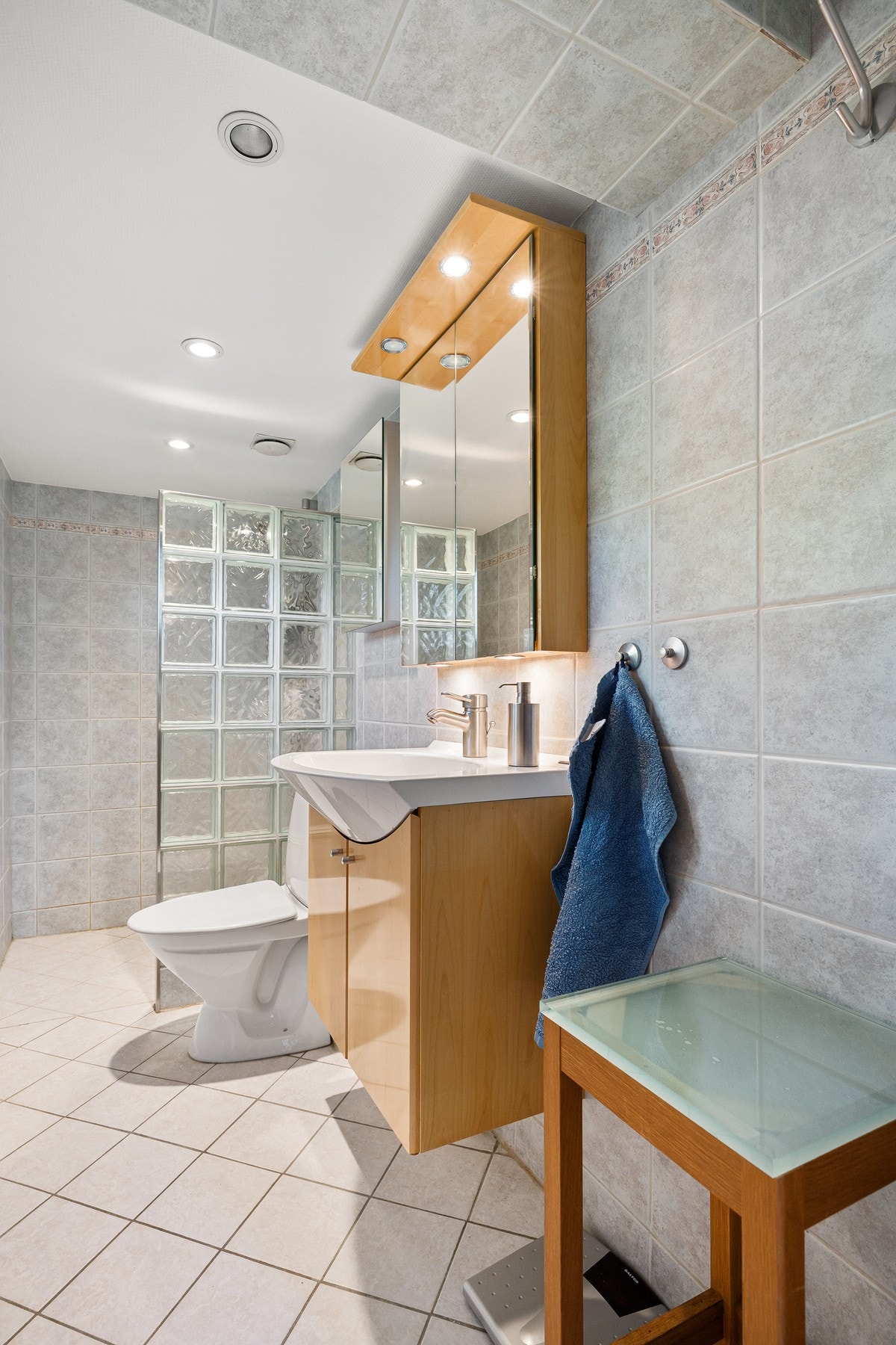 Bad i hovedetasjen med flislagt gulv, varmekabler, servant, wc og dusjløsning. Galleribilde