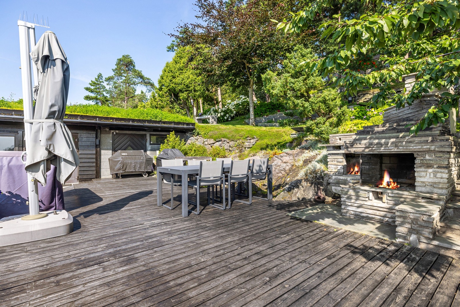 Uteplass med solid fundament og tredekke, med dobbel peis for ekstra komfort. Galleribilde