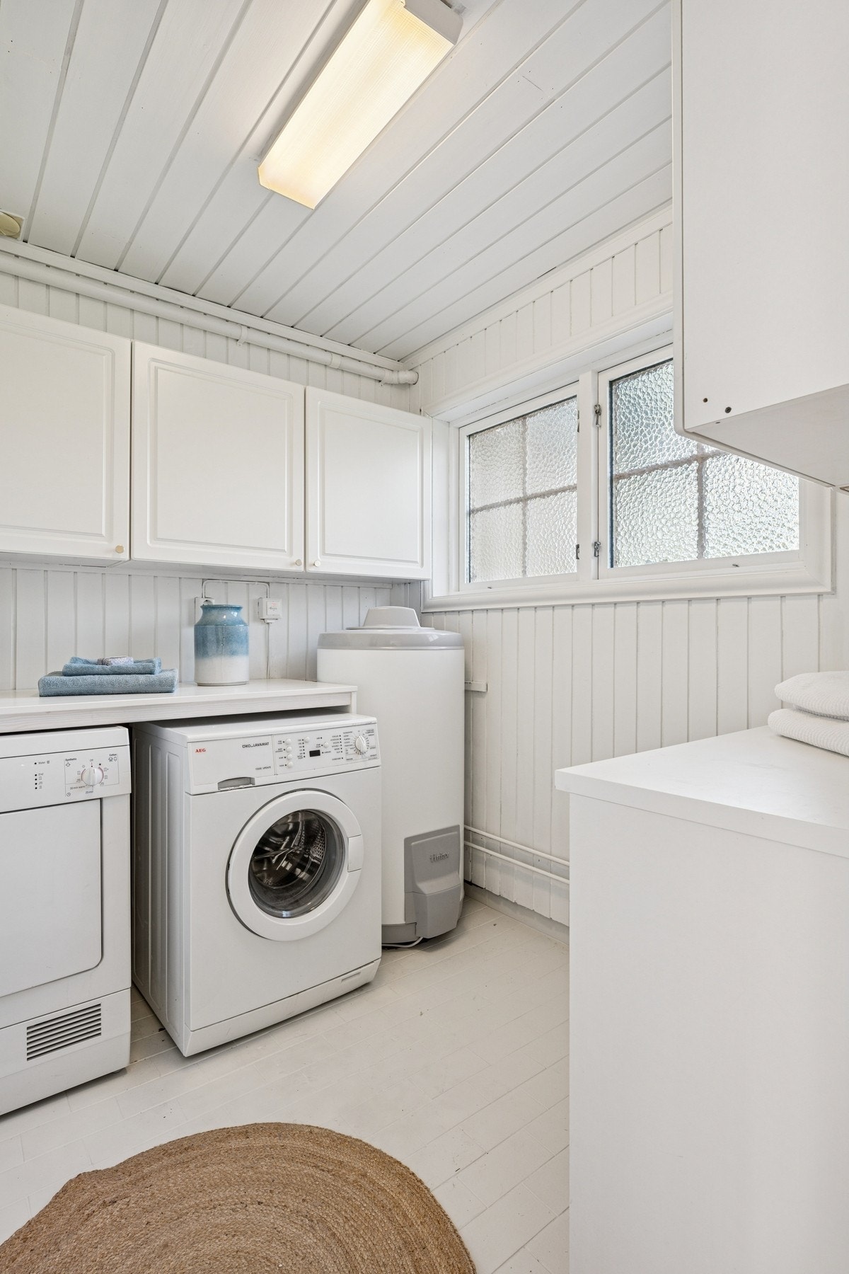 Et lyst vaskerom med plass til vaskemaskin og oppbevaring. Galleribilde