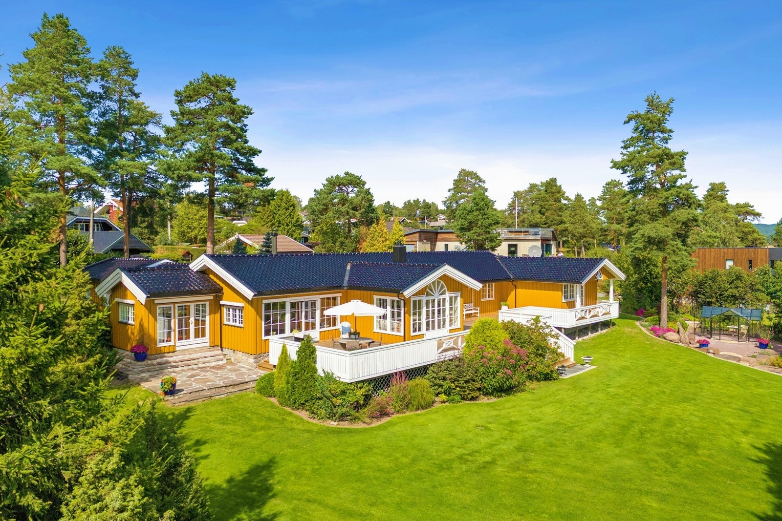 Bilde av fasaden som viser boligens lune plassering i grønne omgivelser. Galleribilde