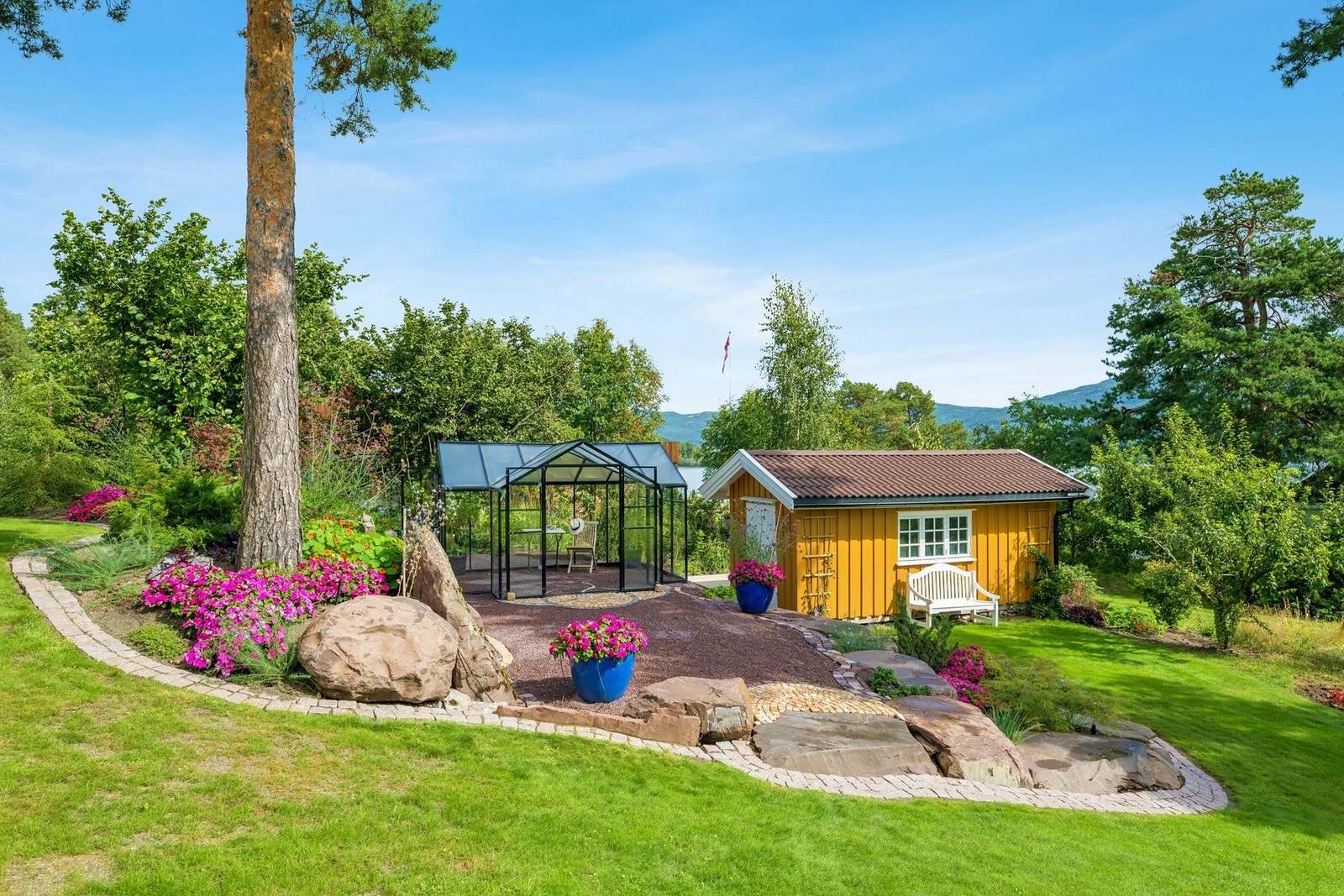 Parkmessig opparbeidet hage med frodige blomsterbed og store plenarealer. Galleribilde