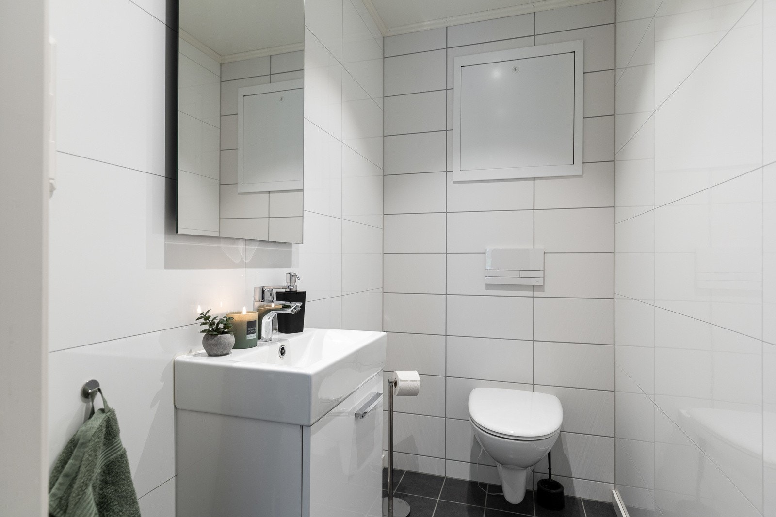 Wc-rommet har samme type gulvfliser som badet, mens veggene er kledd med hvite fliser og hvite våtromsplater i flismønster. Galleribilde