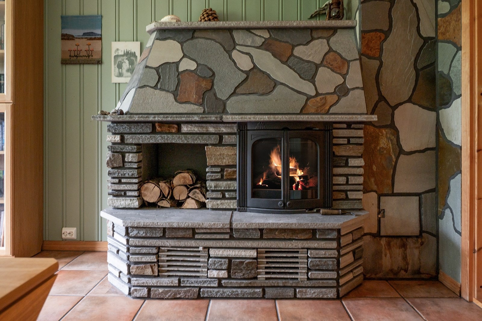 Kjellerstua har en dekorativ peis med peisinnsats Galleribilde