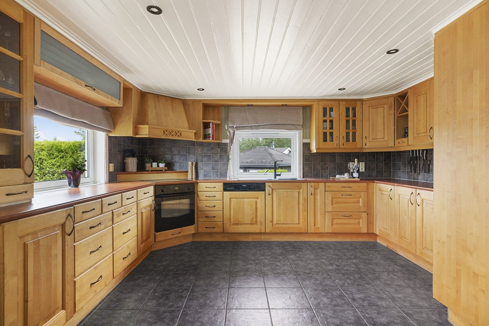 Innredning med profilerte fronter og overskap til tak- fliser på vegg mellom kjøkkenbenk og overskap. Galleribilde