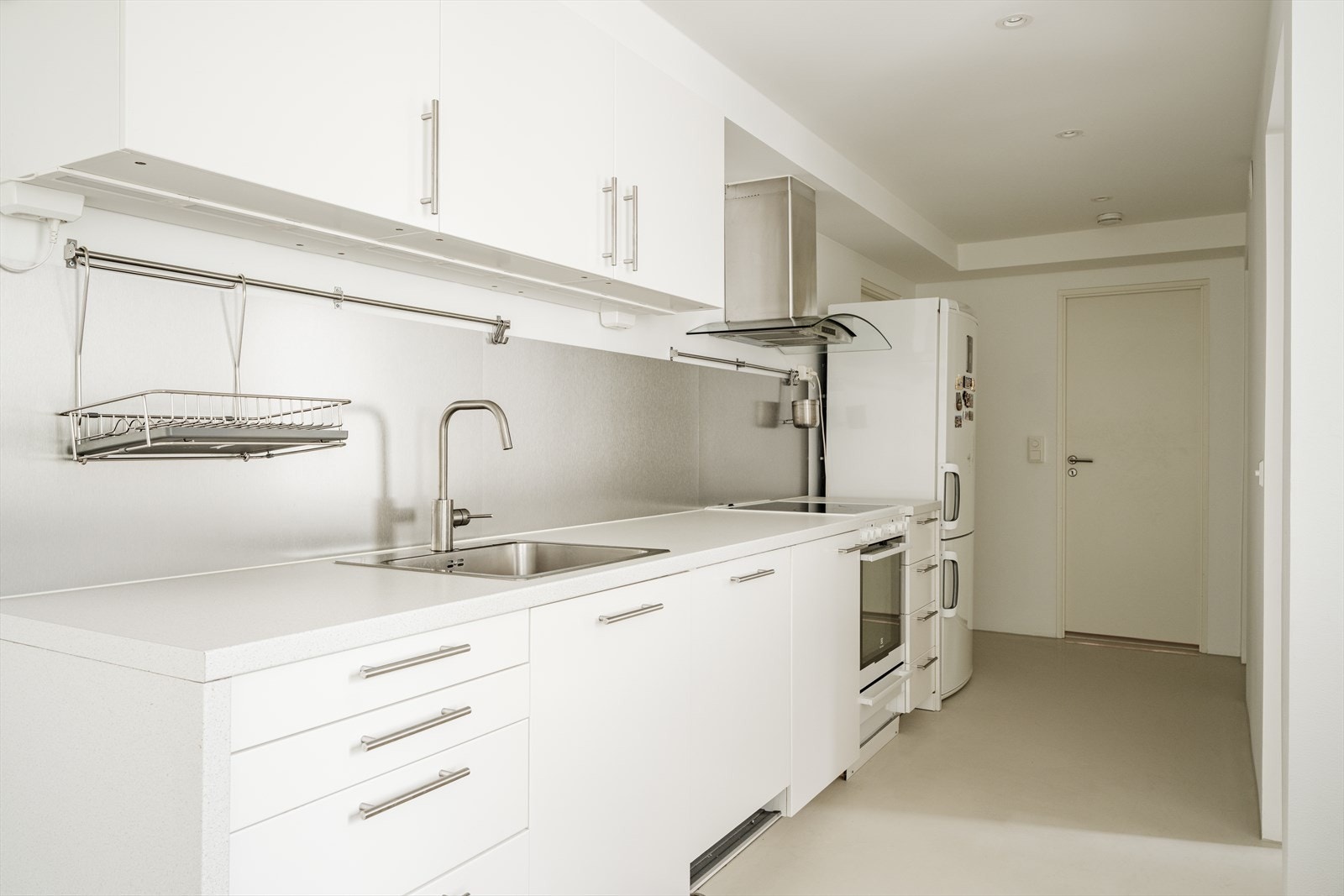 Lyst kjøkken med hvite, glatte fronter og laminat benkeplate. Galleribilde