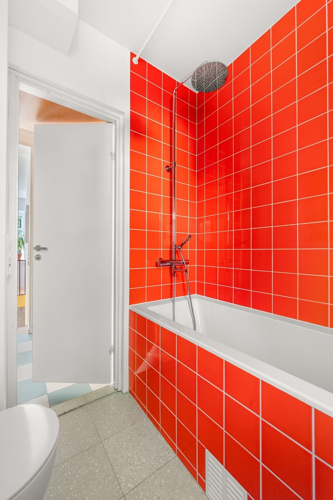 Innredningen består av vegghengt toalett, servant på innredning og badekar med dusjarmatur. Galleribilde