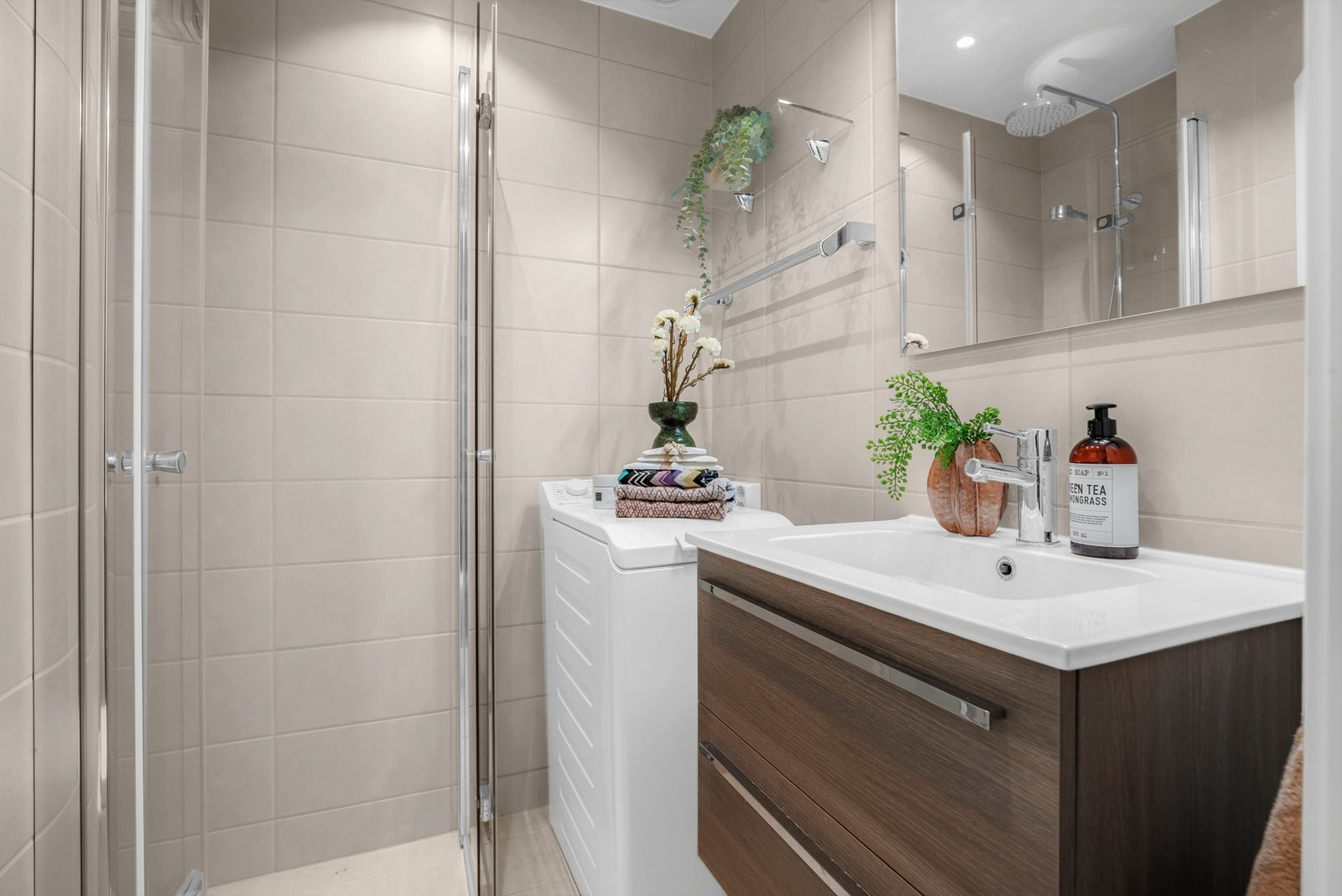 Rommet er utstyrt med dusjhjørne med glassfoldedører, regnfallsdusj, veggmontert toalett og en heldekkende servant med glatte, folierte fronter. Det er også opplegg for vaskemaskin. Galleribilde