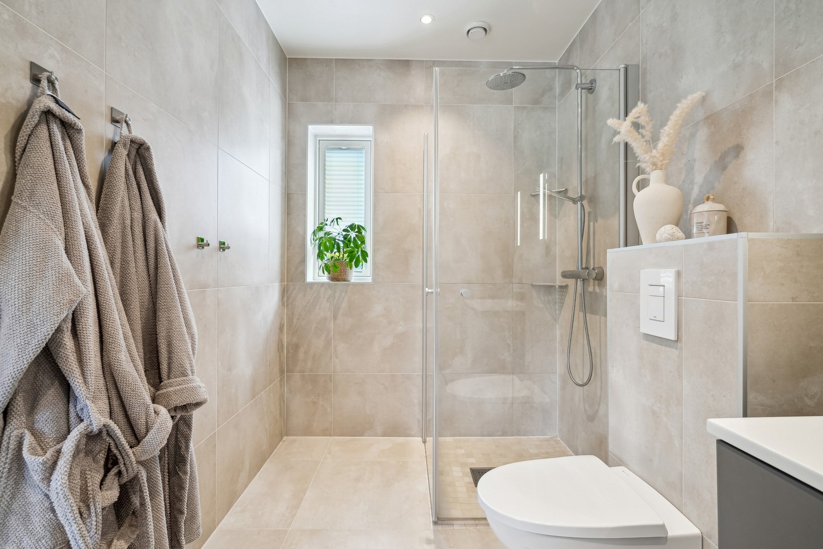 Badet i hovedetasjen har en delikat atmosfære, med store fliser på både gulv og vegger. Led-spotter i himling og varmekabler i gulvet sørger for behagelig komfort. Galleribilde