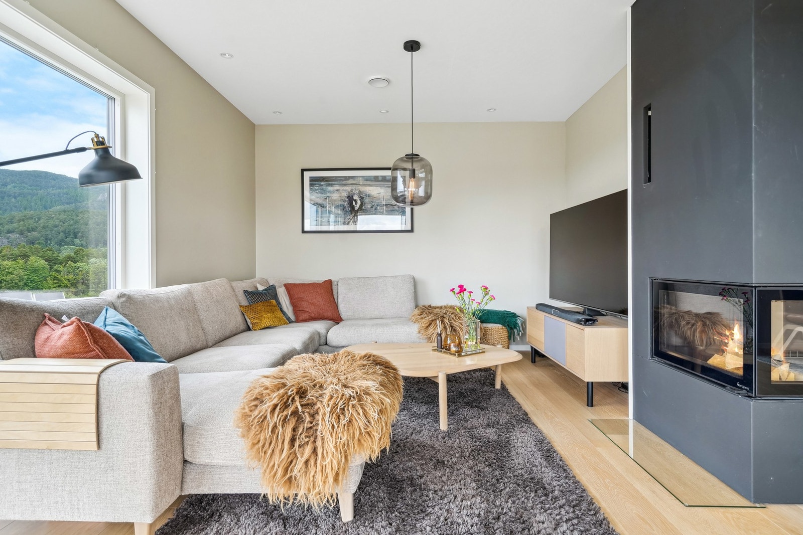 Stuesone med store vindusflater mot vakker natur, peis for ekstra varme og komfort, samt god plass til sofagruppe og TV. Galleribilde