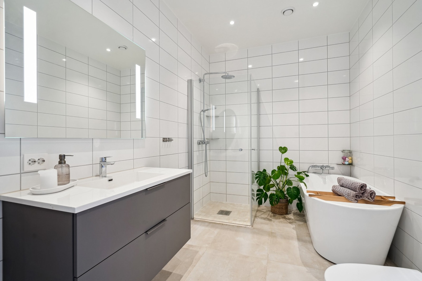 Innredet med servantinnredning med hvit helstøpt servant, speil med integrert belysning, dusjhjørne, badekar og vegghengt toalett. Galleribilde